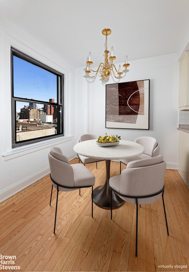 dining room featuring light wood-type flooring, baseboards, and a chandelier