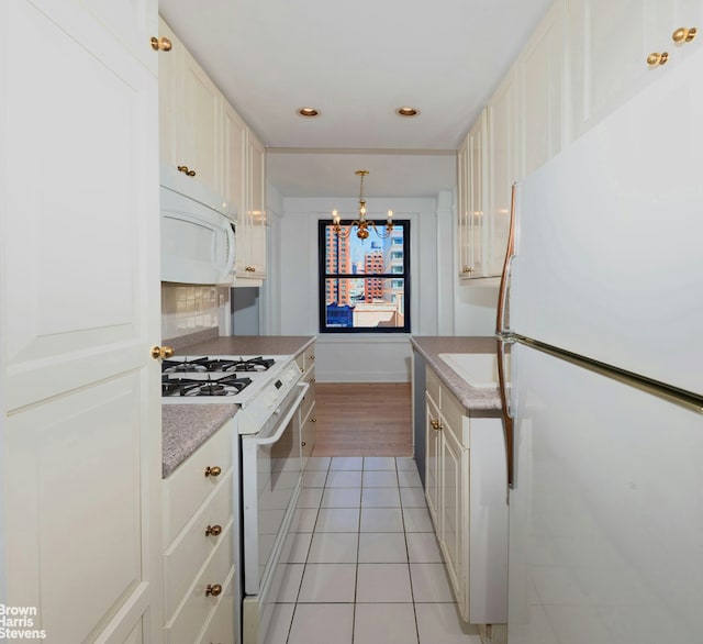 kitchen with white appliances, light countertops, tasteful backsplash, light tile patterned floors, and a notable chandelier