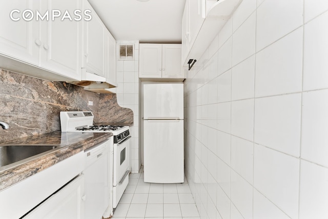 40 Sutton Pl Unit 9J, New York City, NY 10022 - kitchen with white appliances, light tile patterned floors, white cabinets, tasteful backsplash, and dark stone counters