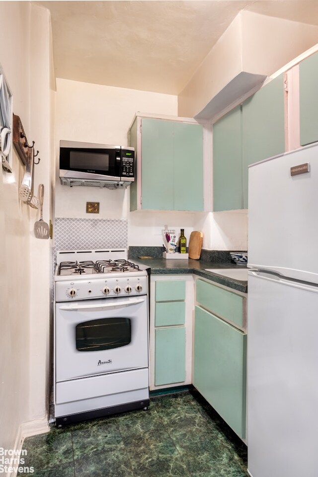 kitchen with white appliances, dark countertops, and a sink