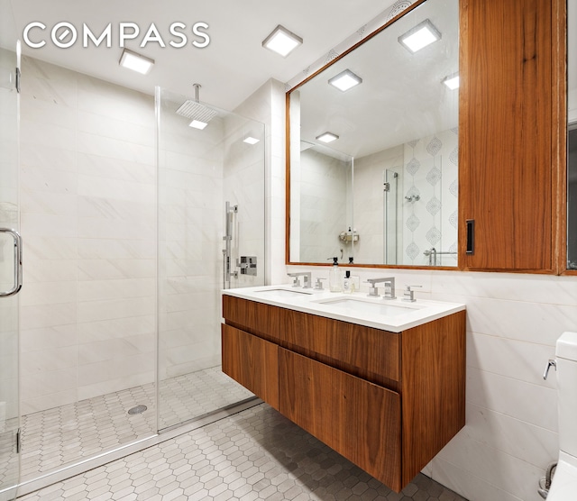 319 Schermerhorn St Unit 5D, New York City, NY 11217 - bathroom featuring a shower stall, double vanity, tile walls, and tile patterned floors