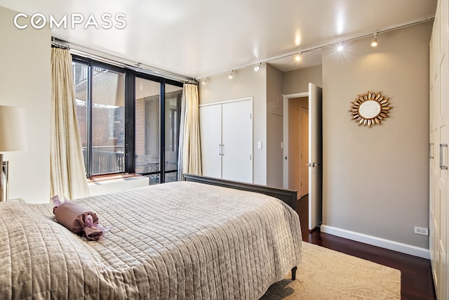 304 E 65th St Unit 10D, New York City, NY 10065 - bedroom with rail lighting, dark wood-style flooring, access to exterior, and a closet