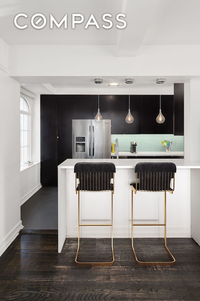 470 W 24th St Unit 2C, New York City, NY 10011 - kitchen featuring stainless steel fridge with ice dispenser, light countertops, a kitchen bar, tasteful backsplash, and dark wood-style floors