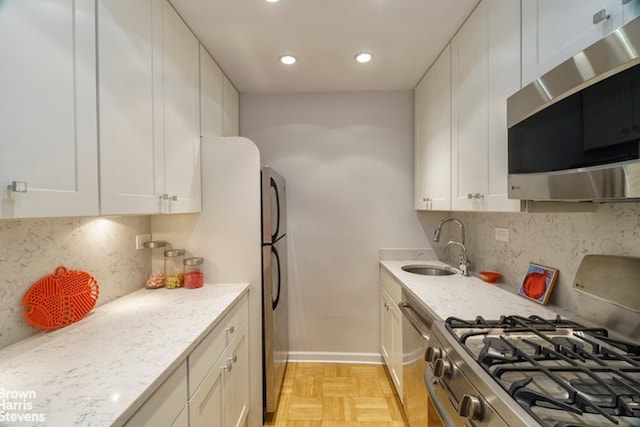 kitchen featuring backsplash, white cabinetry, appliances with stainless steel finishes, and a sink