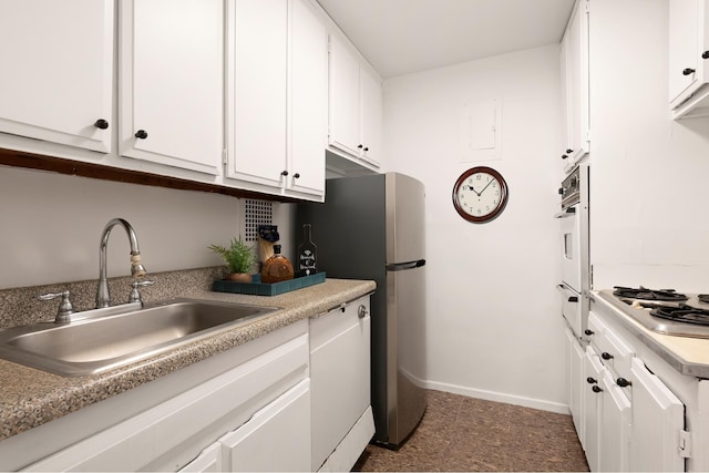 kitchen featuring a sink, appliances with stainless steel finishes, white cabinets, light countertops, and baseboards