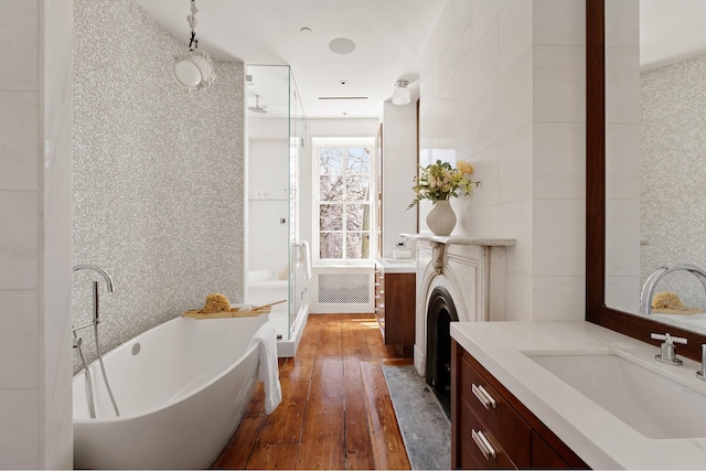 bathroom with hardwood / wood-style floors, a soaking tub, vanity, and a shower stall