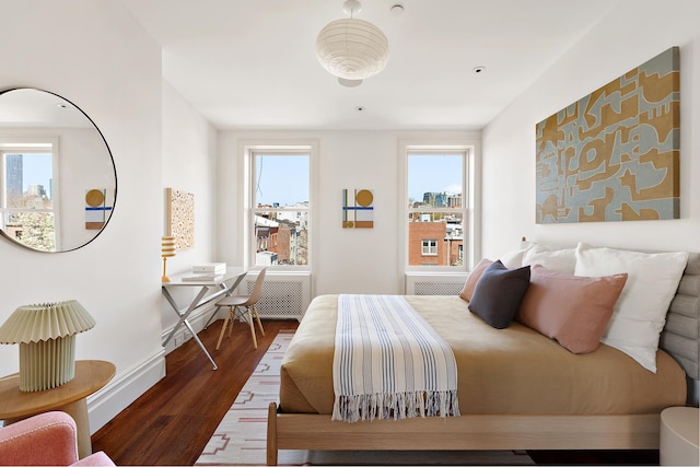 bedroom with baseboards, wood finished floors, and multiple windows