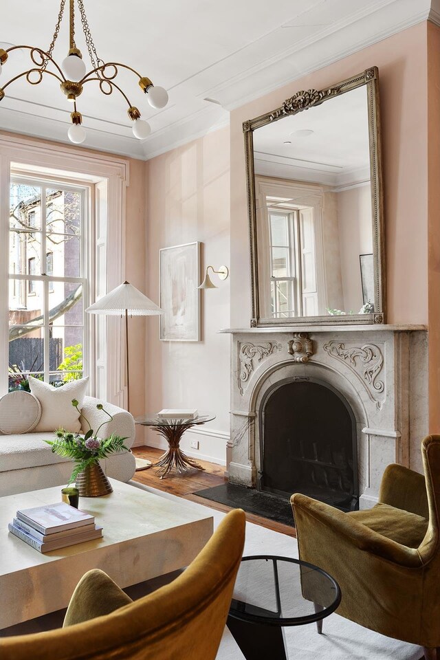 sitting room with baseboards, wood finished floors, a fireplace, and ornamental molding