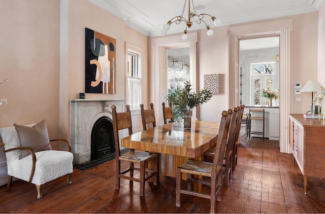 dining area with dark wood-type flooring, ornamental molding, and a notable chandelier