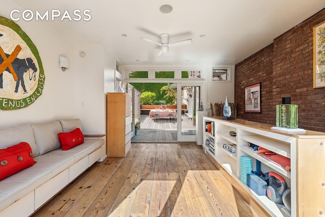living area featuring a ceiling fan, brick wall, and hardwood / wood-style floors