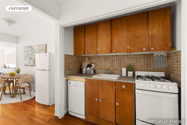 1420 York Ave Unit 4G, New York City, NY 10021 - kitchen featuring white appliances, a sink, wood finished floors, decorative backsplash, and brown cabinets