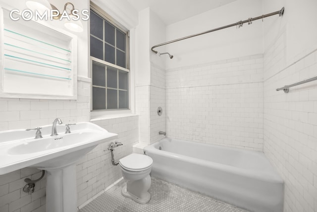 39 5th Ave Unit 2B, New York City, NY 10003 - bathroom featuring tub / shower combination, toilet, tile walls, tile patterned floors, and a sink