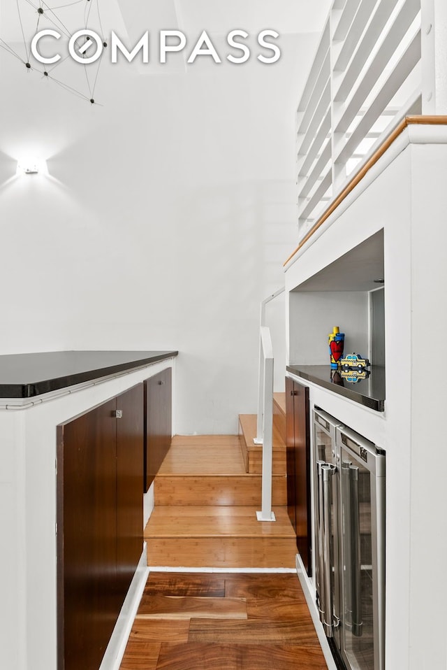 stairway with wood finished floors, beverage cooler, and a dry bar