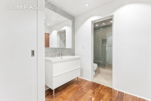 full bathroom with toilet, wood finished floors, a stall shower, decorative backsplash, and recessed lighting