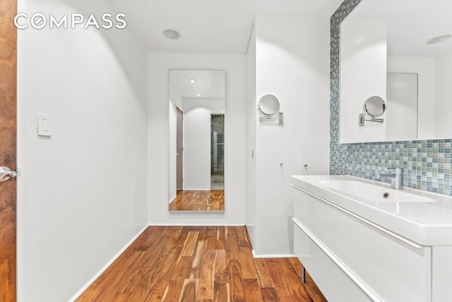 bathroom with decorative backsplash, wood finished floors, vanity, and baseboards