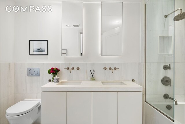 101 Wall St Unit 5Be, New York City, NY 10005 - bathroom with tile walls, toilet, shower / washtub combination, double vanity, and wainscoting