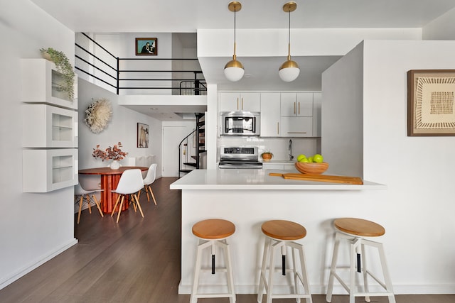 459 12th St Unit A1, New York City, NY 11215 - kitchen with appliances with stainless steel finishes, a breakfast bar, a peninsula, dark wood-style floors, and backsplash