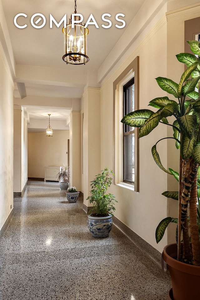 1349 Lexington Ave Unit 8C, New York City, NY 10128 - hallway featuring a chandelier, speckle patterned floor, and baseboards