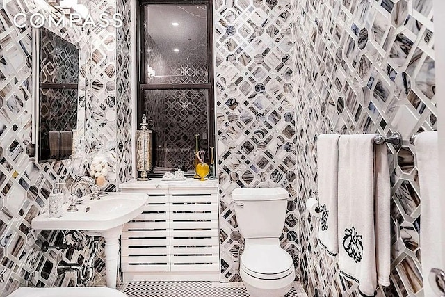 half bath with toilet, tile walls, and tile patterned floors