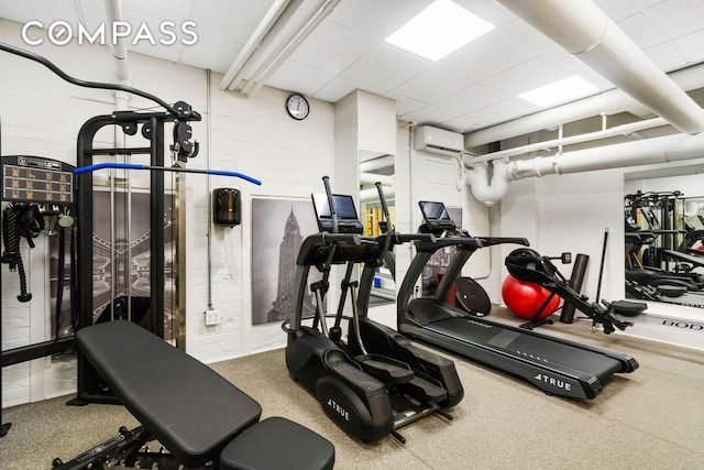 exercise room with an AC wall unit and a drop ceiling