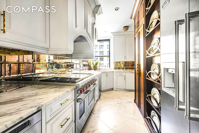 205 W 89th St Unit 6Rs, New York City, NY 10024 - kitchen featuring stainless steel appliances, light marble finish floors, tasteful backsplash, white cabinets, and light stone countertops