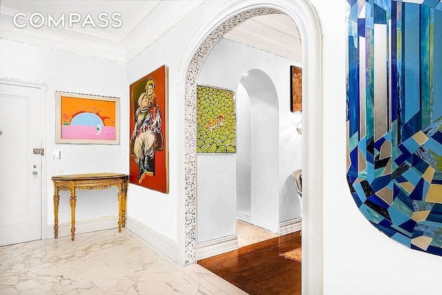 hall featuring crown molding, arched walkways, marble finish flooring, and baseboards