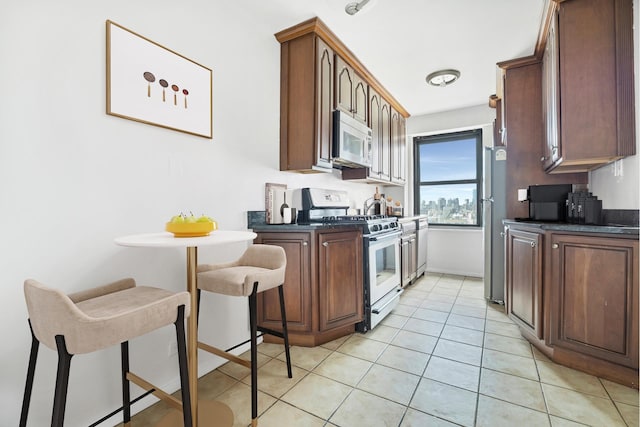 kitchen with stainless steel appliances, dark countertops, light tile patterned flooring, and baseboards