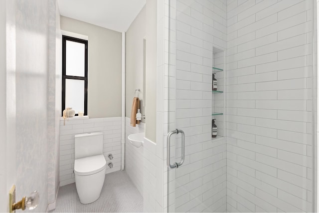 99 E 4th St Unit 4A, New York City, NY 10003 - full bathroom featuring a stall shower, toilet, tile patterned floors, tile walls, and a wainscoted wall