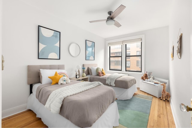 bedroom with light wood-style flooring, ceiling fan, and baseboards