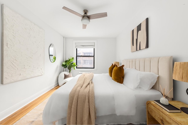 bedroom with light wood-type flooring, baseboards, and a ceiling fan