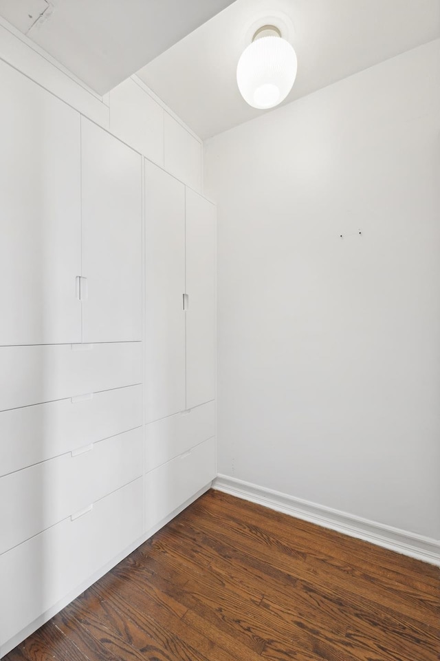 spare room with baseboards and dark wood-style floors
