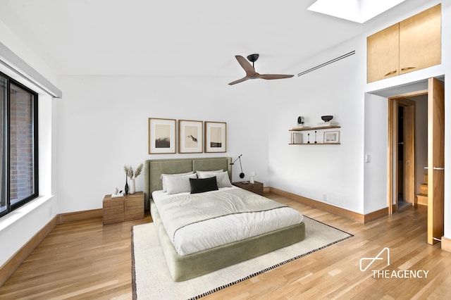 bedroom featuring light wood-style flooring, baseboards, and a skylight