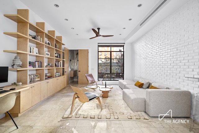 living area with brick wall, ceiling fan, and stone tile flooring