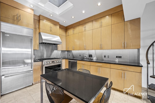 kitchen featuring high end appliances, range hood, recessed lighting, tasteful backsplash, and a sink