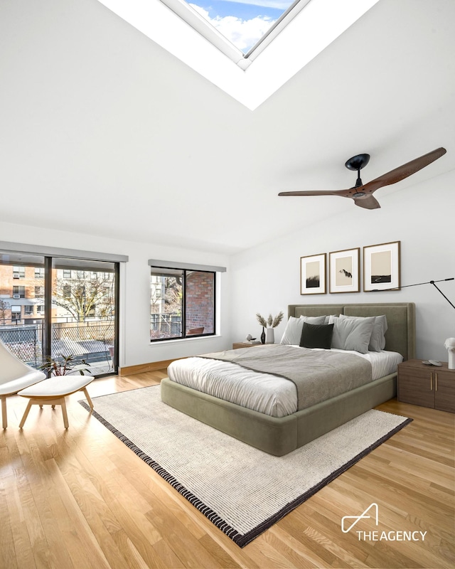bedroom featuring wood finished floors, access to exterior, a skylight, and a ceiling fan