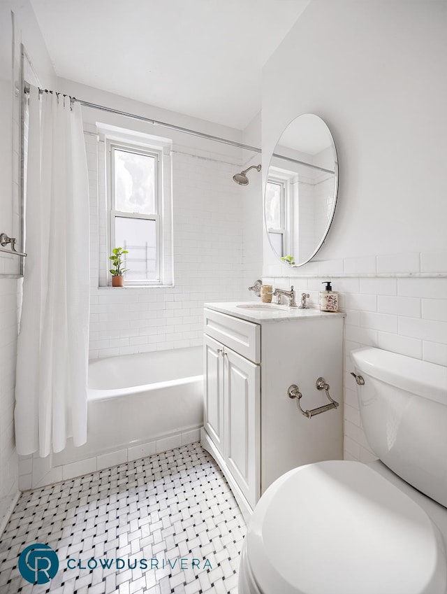 bathroom with toilet, tile walls, vanity, and shower / bath combination with curtain