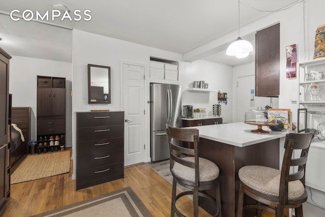 45 Overlook Ter Unit 7J, New York City, NY 10033 - kitchen featuring freestanding refrigerator, a peninsula, wood finished floors, light countertops, and a breakfast bar