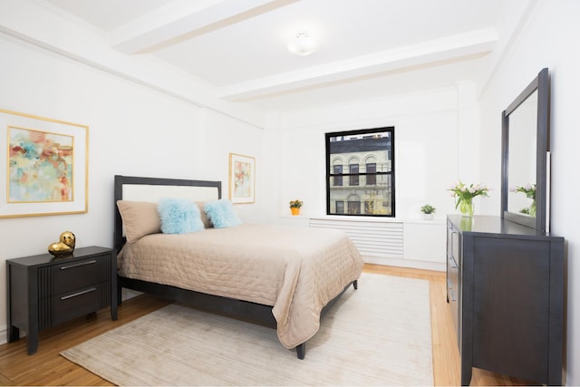 bedroom featuring beam ceiling and light wood-type flooring