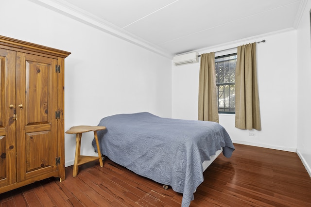 bedroom with a wall mounted air conditioner, ornamental molding, dark wood-type flooring, and baseboards