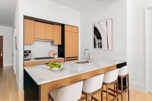 215 E 19th St Unit 2K, New York City, NY 10003 - kitchen featuring a kitchen bar, light stone counters, a peninsula, tasteful backsplash, and stainless steel gas cooktop