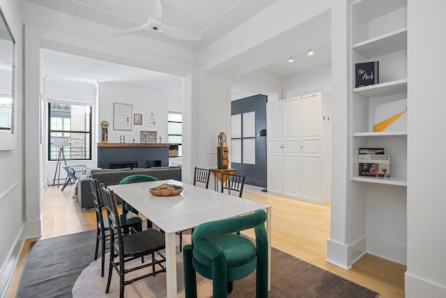 dining area with a ceiling fan, baseboards, built in features, and wood finished floors