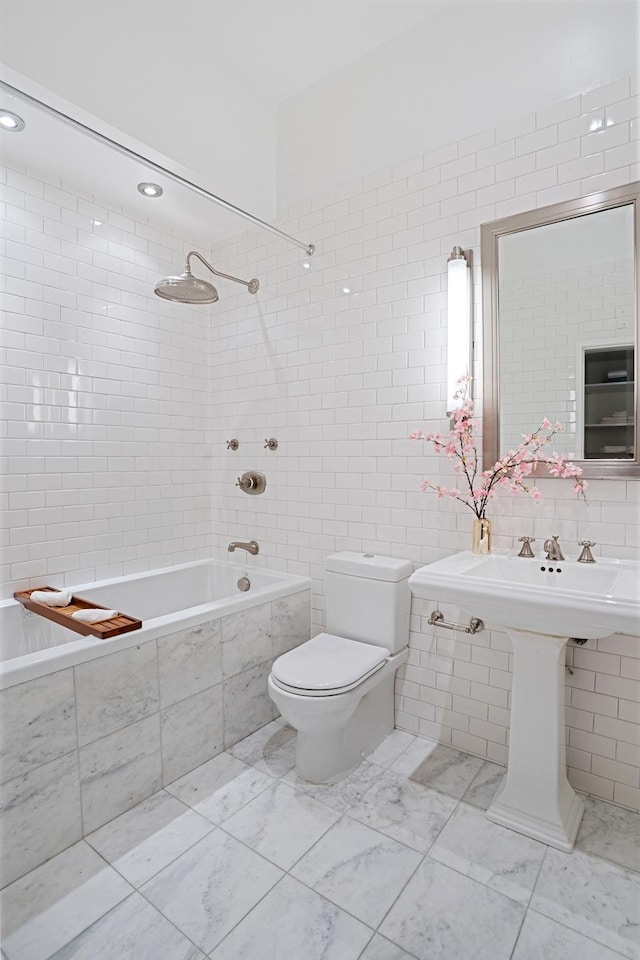 full bathroom with toilet, tiled shower / bath, and tile walls