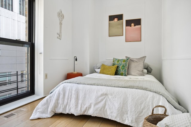 bedroom with visible vents, wood finished floors, and multiple windows