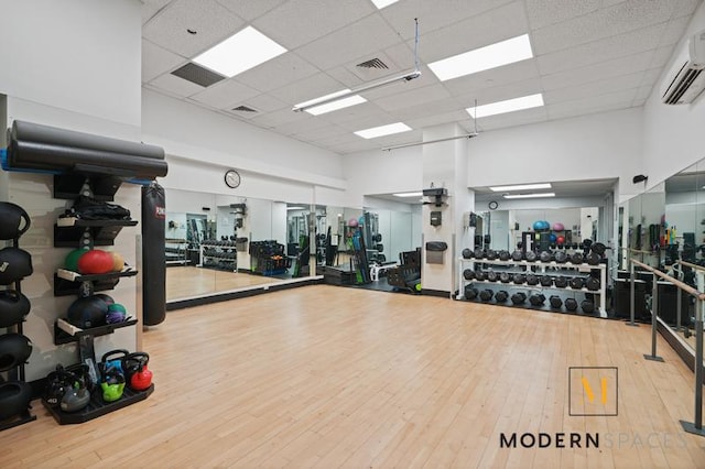 4-74 48th Ave Unit 8-M, New York City, NY 11109 - exercise room with an AC wall unit, a towering ceiling, a drop ceiling, and wood-type flooring