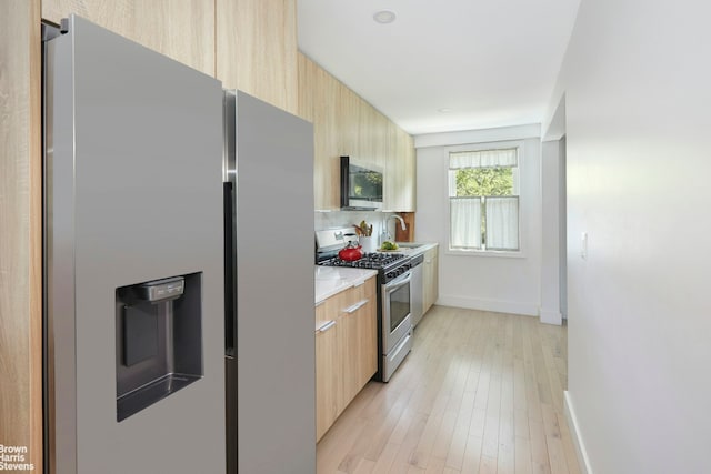 kitchen with stainless steel appliances, modern cabinets, a sink, and light brown cabinetry