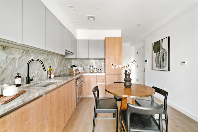 44 Box St Unit 5C, New York City, NY 11222 - kitchen featuring light stone counters, light wood finished floors, oven, modern cabinets, and decorative backsplash
