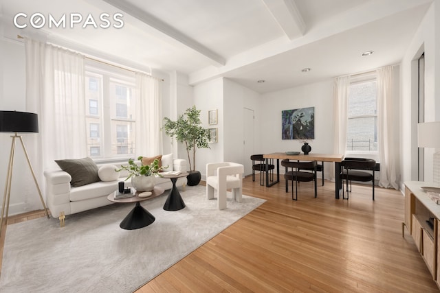 living area featuring beam ceiling and light wood-style floors