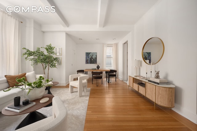 living room with beamed ceiling, light wood-type flooring, and baseboards