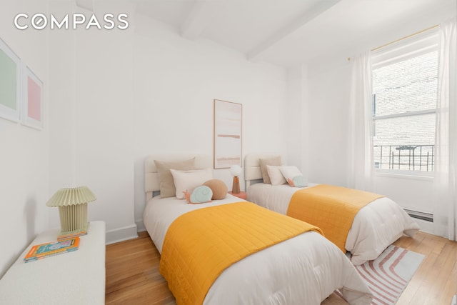bedroom with hardwood / wood-style flooring, beamed ceiling, and a baseboard radiator