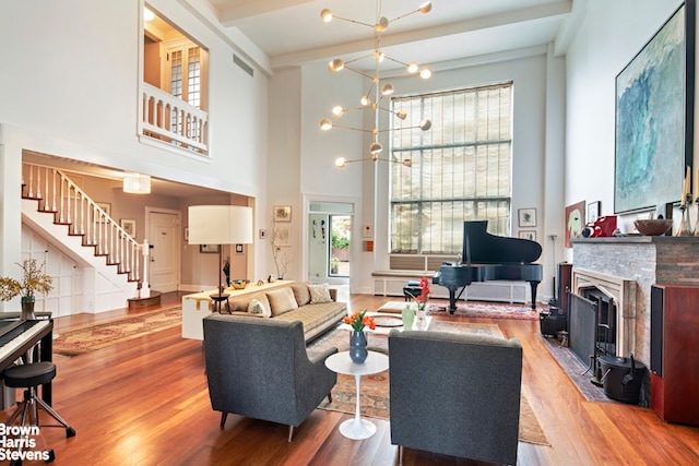 living area featuring a towering ceiling, visible vents, wood finished floors, stairway, and a fireplace